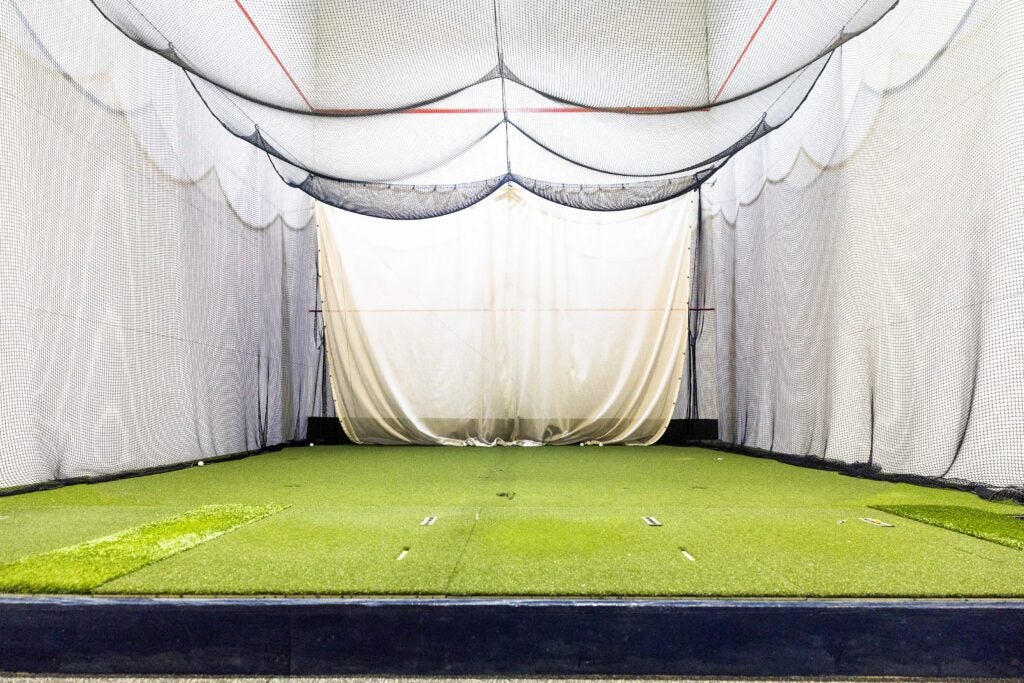 Floor-level view of an empty golf room with netting